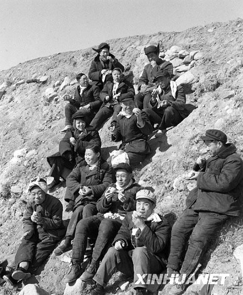 (资料照片)1958年3月2日,北京天桥商场下放干部在南口果木农场的荒地上种植果树。图为他们在荒地沙坡上吃窝窝头。新华社记者安康摄
