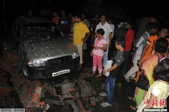 图为印度西里古里，居民聚集在一辆被石块损毁的汽车旁查看。