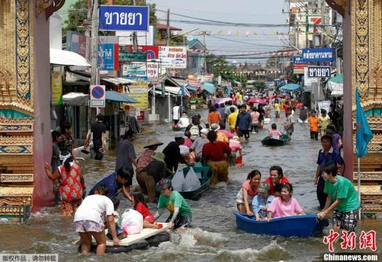 10月10日，泰国大城府，人们在一片水淹地区涉水通行。泰国正在遭遇半个世纪以来最严重的洪涝灾害，据泰国内政部公布的最新数据，持续肆虐的 洪灾已经造成了261人死亡，4人失踪。  