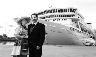 8日，英国南安普敦港，两名游客身着20世纪初服饰准备参与“重温泰坦尼克之旅”，远处是“巴尔莫勒尔”号游轮。