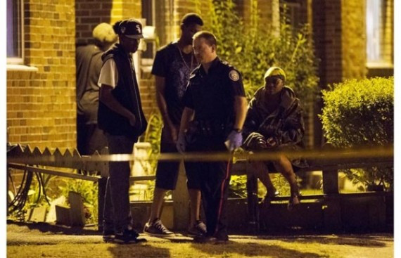 A police officer walks the crime scene as people look on following a shooting in Scarborough, a suburb in east Toronto