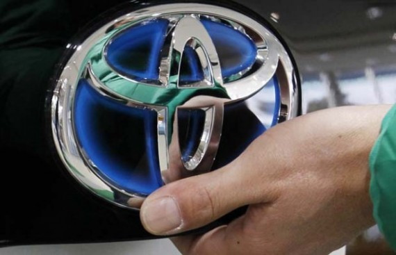 A man touches the Toyota logo on Toyota Motor Corp's newest Prius hybrid car at its showroom in Tokyo