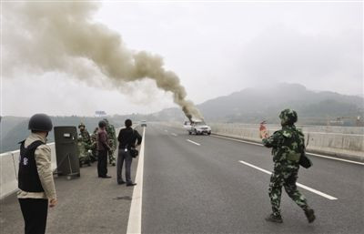 一名武警手持灭火器走向冒烟的奔驰车。警方朝劫持案事发车里施放了催泪瓦斯。苍溪县公安局供图