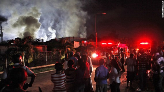 Residents watch firefighters battle a blaze in Kingston, Jamaica, on Friday. The fire, which destroyed the home, was started by a faulty generator that was triggered when Sandy caused a blackout, firefighters said.