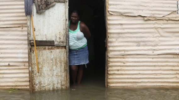 A woman stands at the entrance of her house surrounded by flood water after heavy rain in Santo Domingo on Thursday.