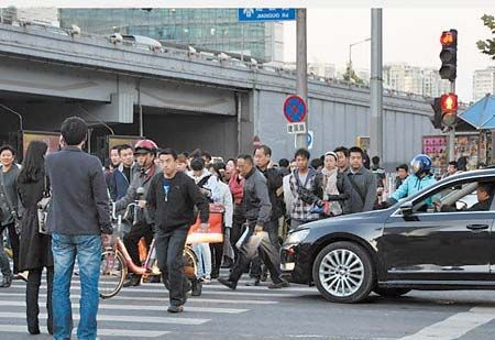 10月17日，北京市某十字路口，红灯下，行人们“组团”集体过马路。(国新提供)