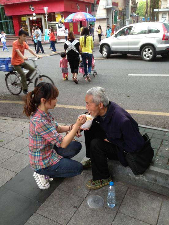 路人感动：90后女孩单膝跪地 给街头乞讨残疾老人喂饭(图)