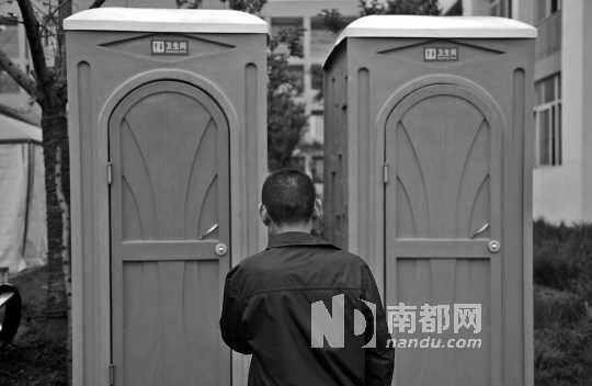 灾区厕所紧张,一灾民在临时厕所外等待如厕。东方IC