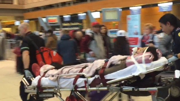A passenger from Air Canada Flight 88 is moved through the Calgary airport on Wednesday afternoon.