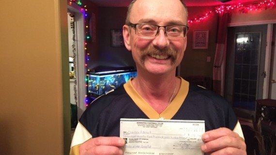 Charles Ritchot holds up his 50/50 prize cheque for $178,748 Tuesday night.