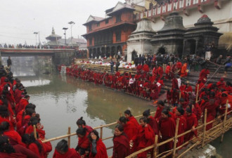 尼泊尔妇女深穿红袍 半裸洗圣浴祈福