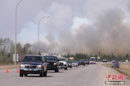 当地时间5月7日，加拿大阿尔伯塔山林大火继�肆虐，当天风向大变，过火面积达到2000平方公里，比�前一天扩大一倍。图为民众沿着公路向南撤离。 �新社记者 徐长安 摄