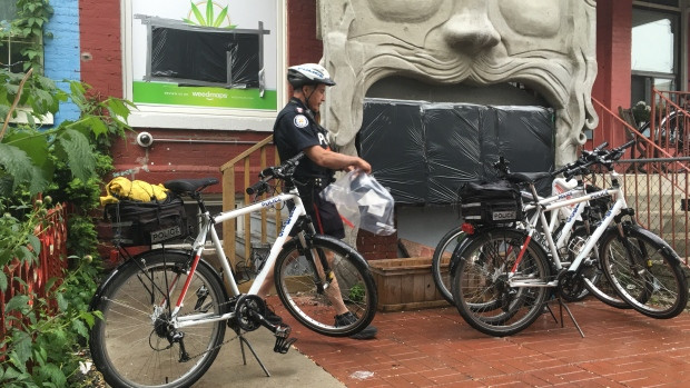 A Toronto police officer bags evidence outside a marijuana dispensary in Toronto's Kensington Market. Police executed search warrants at a number of dispensaries where they allege trafficking has occurred.