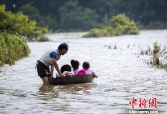 江西暴雨过后 村民用木桶推三个孙女上学