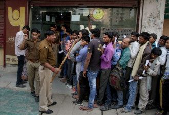 印度废钞乱象：警察手握棍棒维持排队秩序
