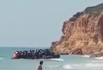 海滩一幕惊呆游客：一群偷渡客漂来开始爬悬崖