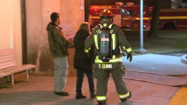 A Toronto firefighter helps two people after a fire on the 10th floor of an apartment building in Scarborough early Wednesday. Four residents suffered minor smoke inhalation, one was taken to hospital.