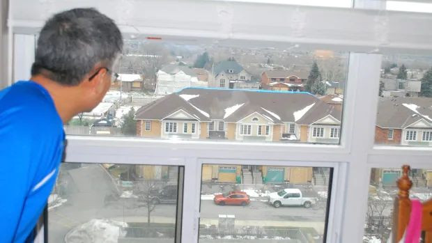 Frank Mo looks down at the repairs on his town home from his rented sixth-floor condo.