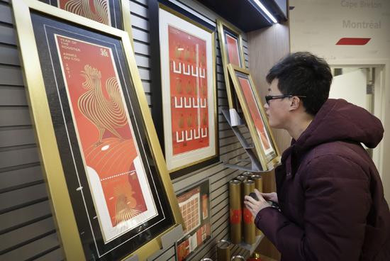 一名男�在一家邮局欣赏�国鸡年生肖邮票相关纪念品