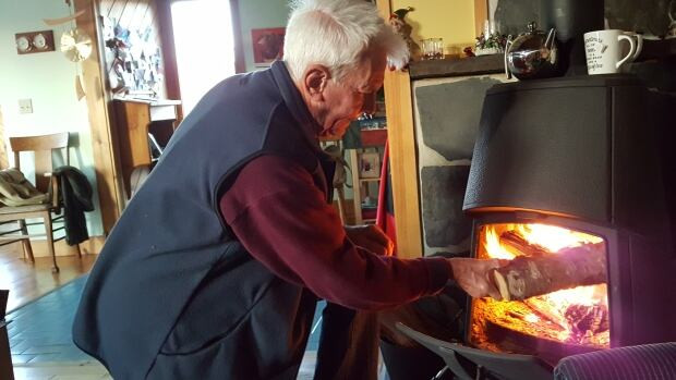 Abe Croft, 69, stokes his fire as he waits for power to come back at his home near Martins Point, N.S.
