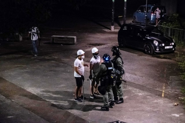 7月21日,香港�方在元朗与手持�器的男�讲话。不久后,一群亲�国的暴徒在火车站�击人群。