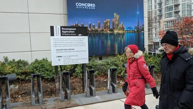 People walk past a notification about two proposed condo towers in Toronto. 
