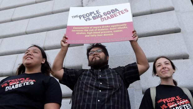 Jesus Alonso, centre, holds a sign between other volunteers after San Francisco backers of a tax on sugary beverages announced they had enough signatures to put the measure on the city's November ballot.