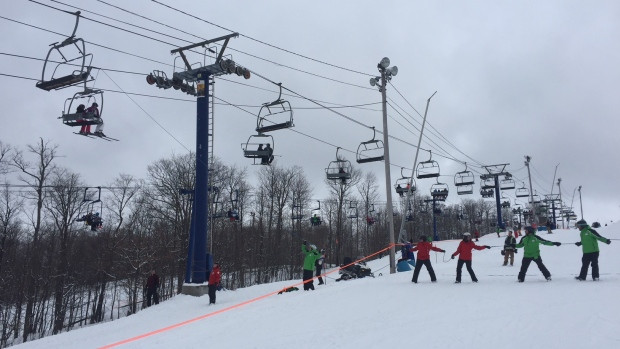 Skiers are being lowered from the lift with a rope and harness.