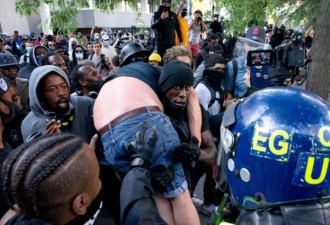 一群黑人抗议者将一名受伤白人托举运给警察