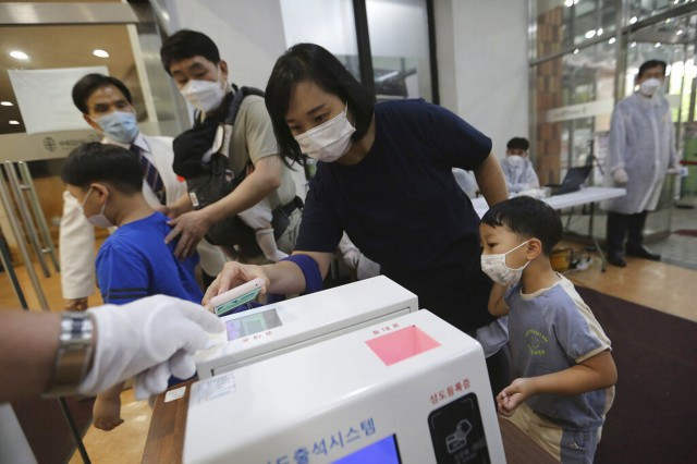 韩国新冠肺炎疫情：7月5日，首尔一名基督徒在进入教会前，在一部仪器上扫描二维码，协助政府防疫工作。（AP）