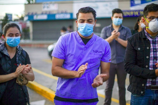 危地马拉新冠肺炎疫情：7月11日，几名医生在危地马拉市向�去的同事表示敬意。（AP）