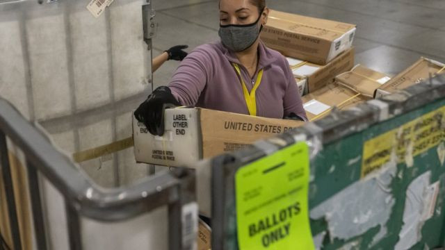 在俄勒冈州，一名邮政工作人员卸下数以千计装满选票的盒�。