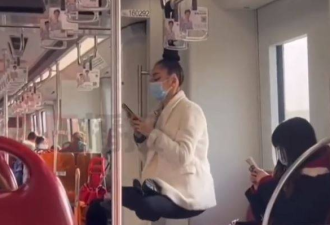 头发系扶手上 女子地铁凌空盘坐玩手机