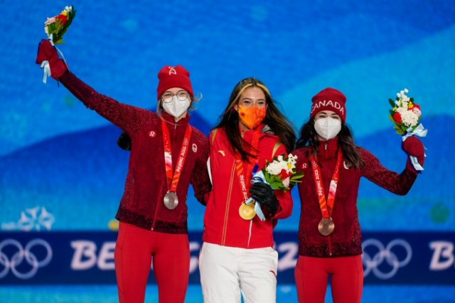 Three athletes on the podium with gold, silver and bronze medals aound their neck