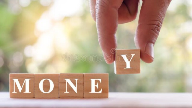 The hand is picking up a wooden block with the lettering in front to make a sense of money. Hands are picking up wooden blocks with letters in front to give a stock photo