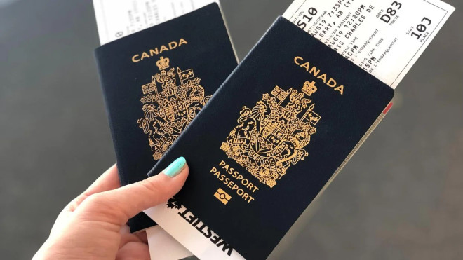 ​Person holding two Canadian passports with flight boarding passes.