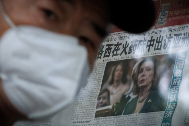 A man stands in front of a glass cabinet displaying the Global Times newspaper that features an article about U.S. House of Representatives Speaker Nancy Pelosi's Asia tour, in Beijing