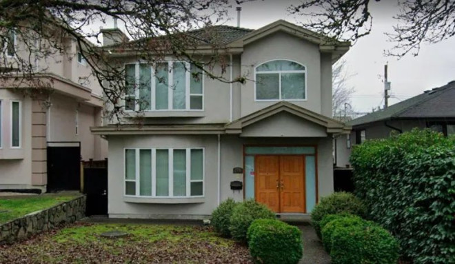 A Google Streetview image shows a two-storey beige house with green-tinted glass in the windows and dead leaves on the neatly mowed front lawn.