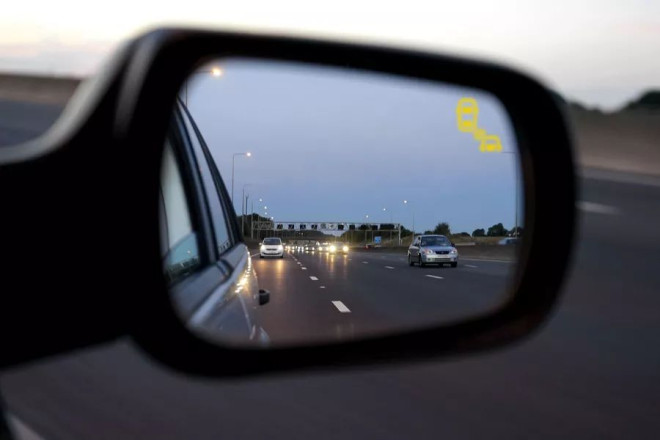 A blind spot detection warning indicator on a car mirror.