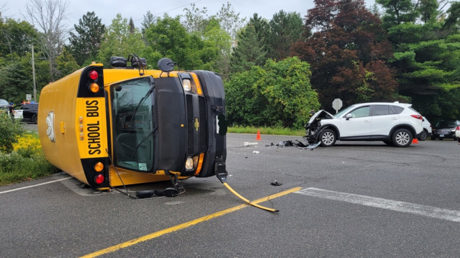 A school bus rests on its side next to a damaged SUV in the intersection of The Gore Road and Patterson Side Road in Caledon, Ont., on Wed., Sept. 7, 2022. (OPP/Twitter)