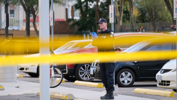 A Toronto police officer gathers evidence at the scene of a shooting in Scarborough that left a boy dead. (Simon Sheehan/CP24)
