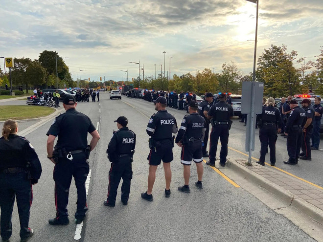 Police officers standing outside the coroner’s office as the fallen officer arrives.