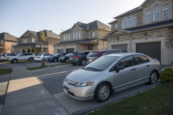 Townhomes, and multiple cars in driveways on Passfield Trail. in Brampton’s L6P postal code area, are photographed on May 12, 2021. The L6P postal code area in Brampton, Ont. has seen high positivity rates for COVID infection and many essential workers live in this area, or live in multiple generation households.