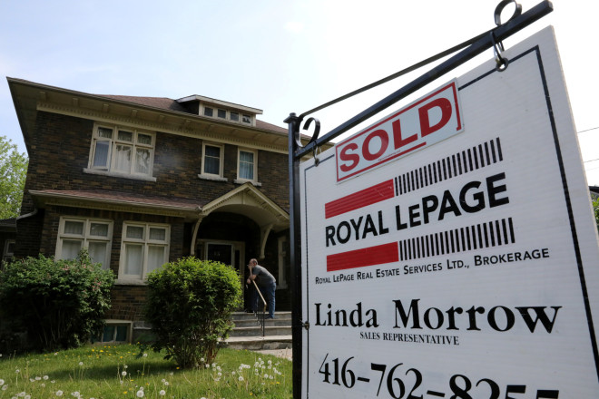 A realtor's sign stands outside a house for sale in Toronto