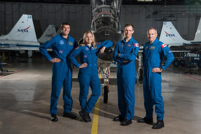 Canadian Space Agency astronauts Jeremy Hansen, Jenni Sidey-Gibbons, Joshua Kutryk and David Saint-Jacques pose together in front of a plane.