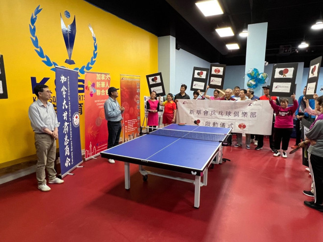A group of people standing around a ping pong table  Description automatically generated