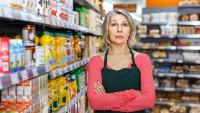 A women stands in a grocery isle with her arms folded.