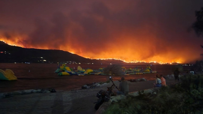 Onlookers watch the McDougall Creek wildfire threatening parts of West Kelowna, B.C., on Aug. 17, 2023. 