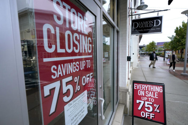 In this Sept. 2, 2020 photo, aassers-by walk past a business storefront with store closing and sale signs in Dedham, Mass.The coronavirus and the drastic measures put in place by government officials to try to control its spread had a severe toll on many small businesses in the U.S.(AP Photo/Steven Senne)