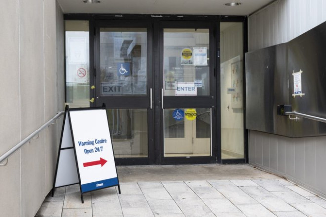 A sandwich board that says Warming Centres open 24/7 in front of a door.